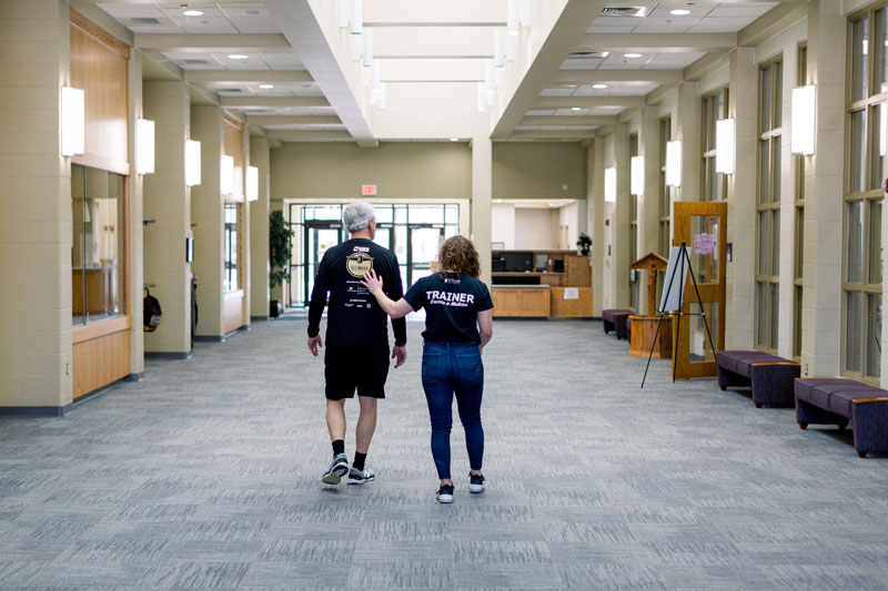 A student walking down the hallway with an elderly man