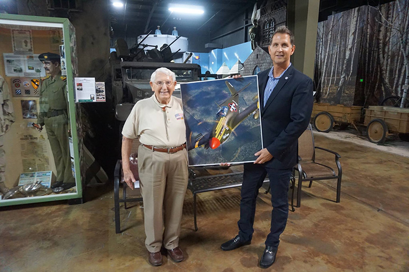 Two men with a picture of an A-36 dive bomber plane