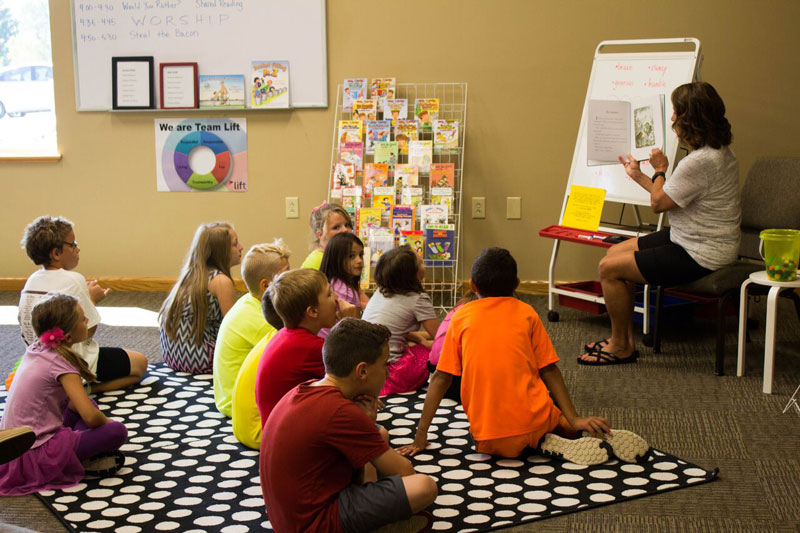 A Taylor student reading a book to a class of children