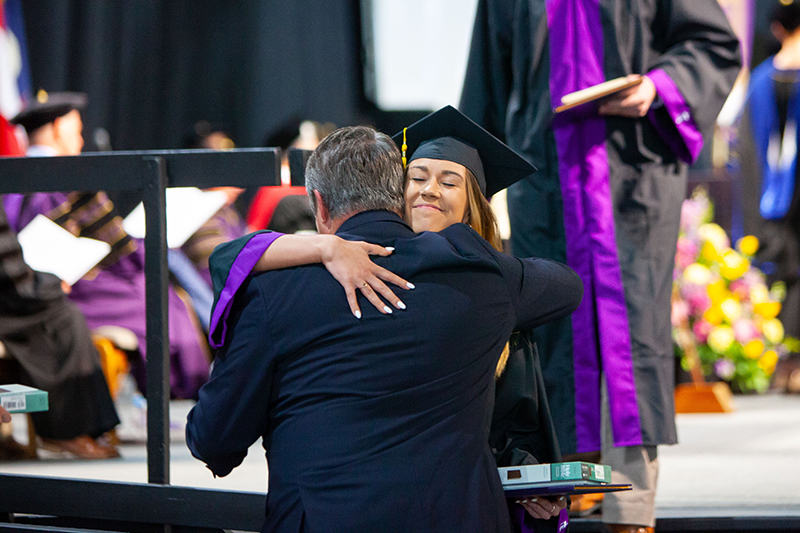 student hugging a professor at graduation