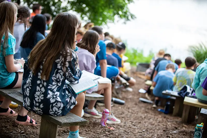 children listen to a message outside on benches
