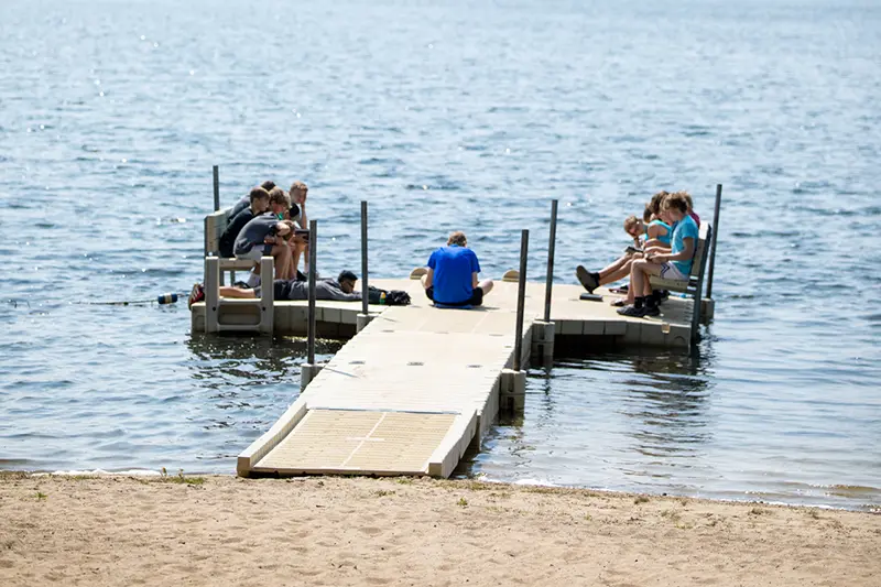 a group of boys do Bible study on a dock by the lake