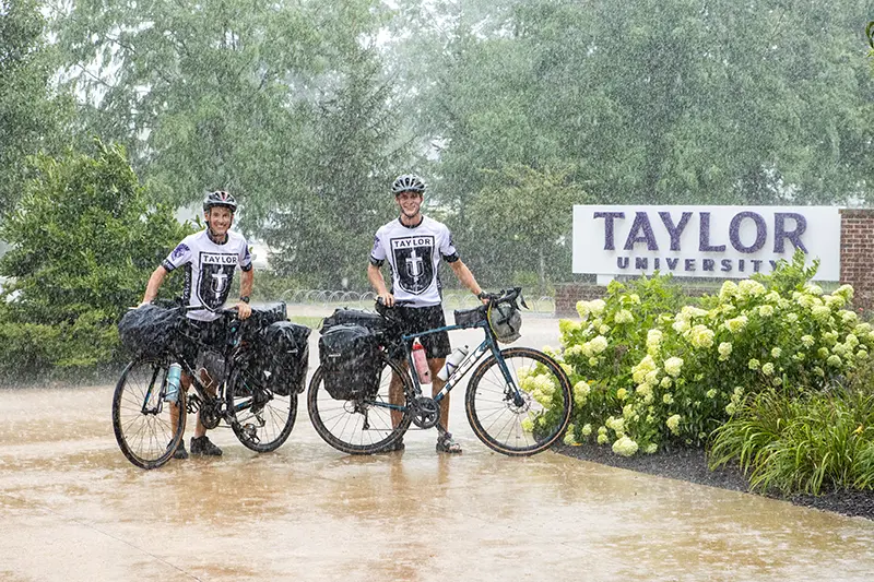 Colton and Daron with bikes in front of Taylor sign