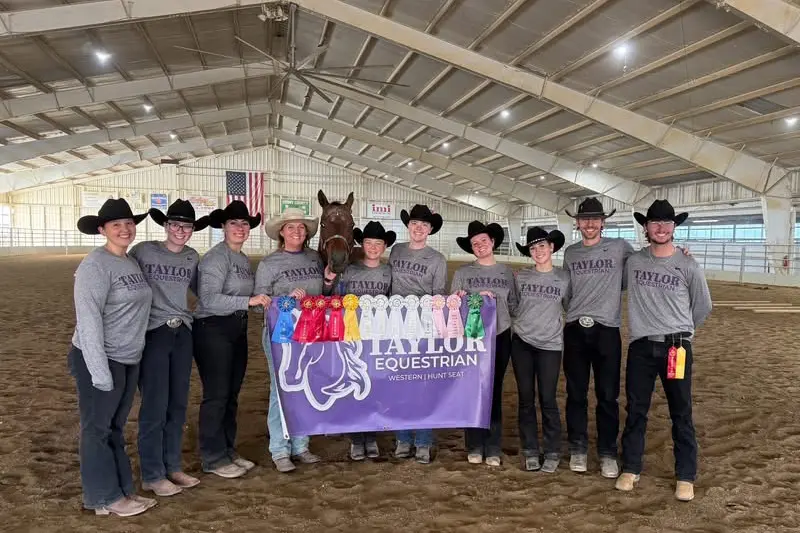 Taylor Equestrian holds banner and ribbons after competition.