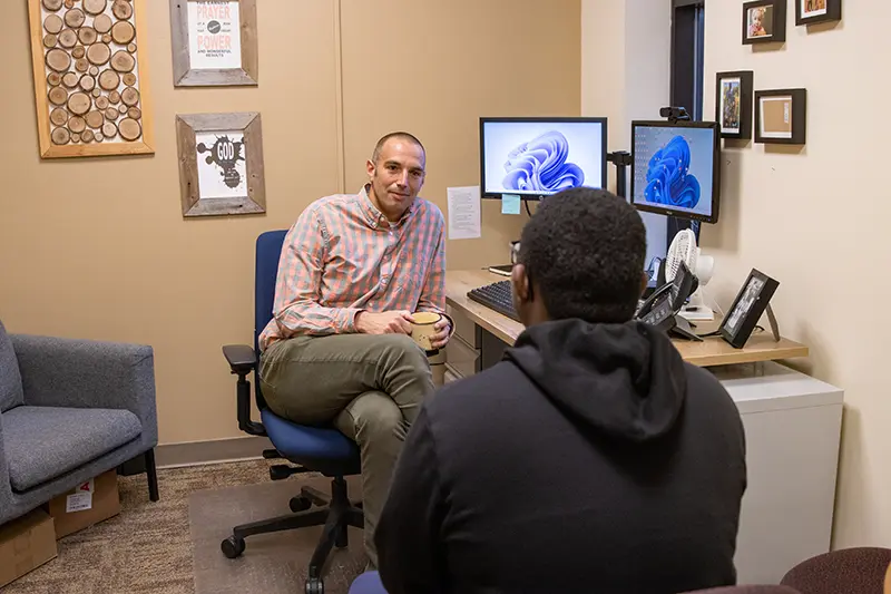 Dr. Scott Barrett talks with a student in his office