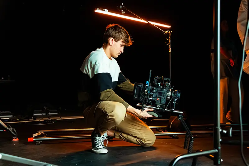student holds film camera on set
