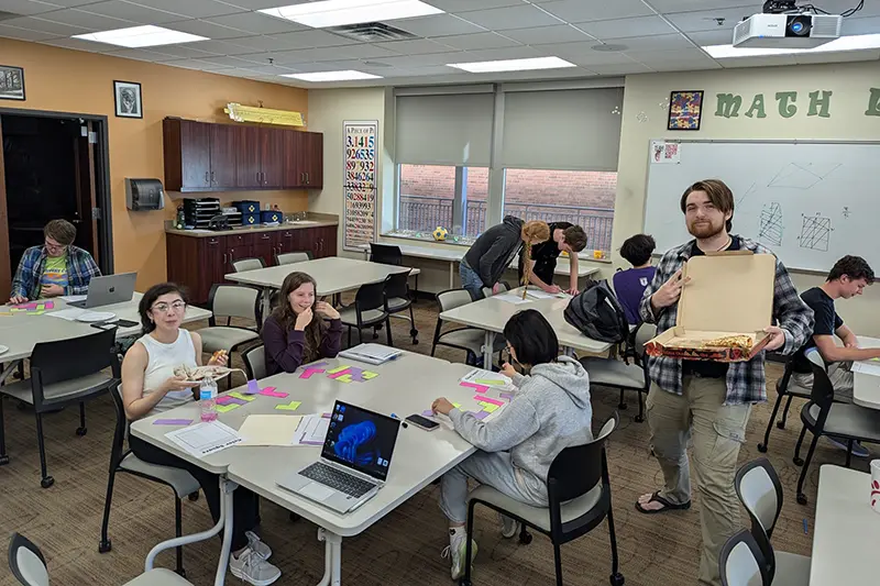 students in classroom practice math and eat pizza