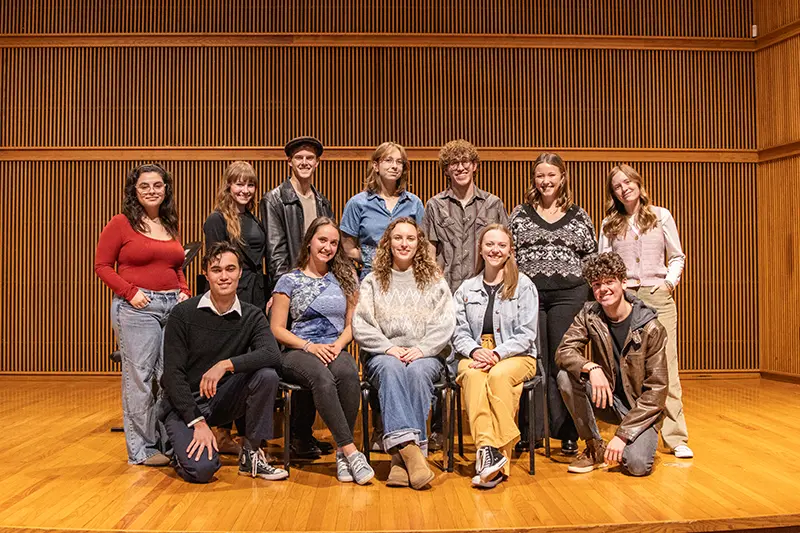 students pose on recital hall stage