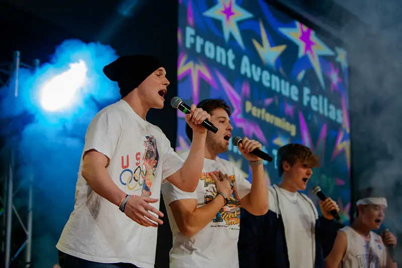 four guys singing on stage