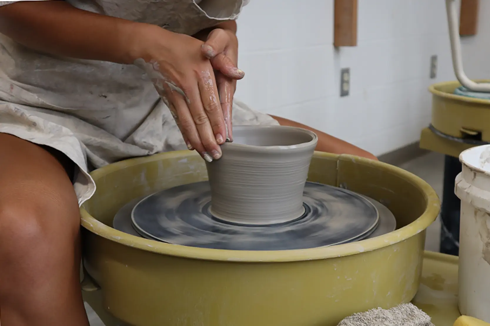 Evie shaping a pot on the wheel
