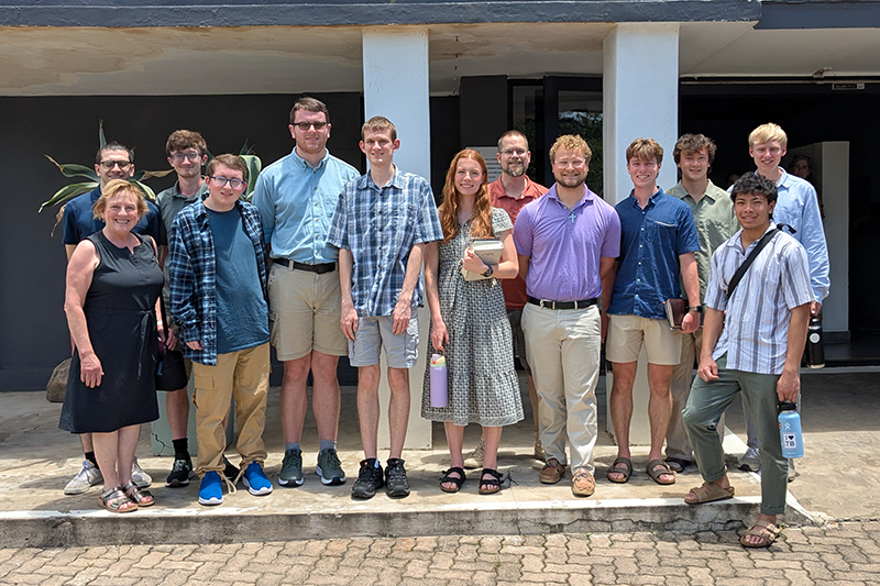 Large group of students and faculty posing outside a building.