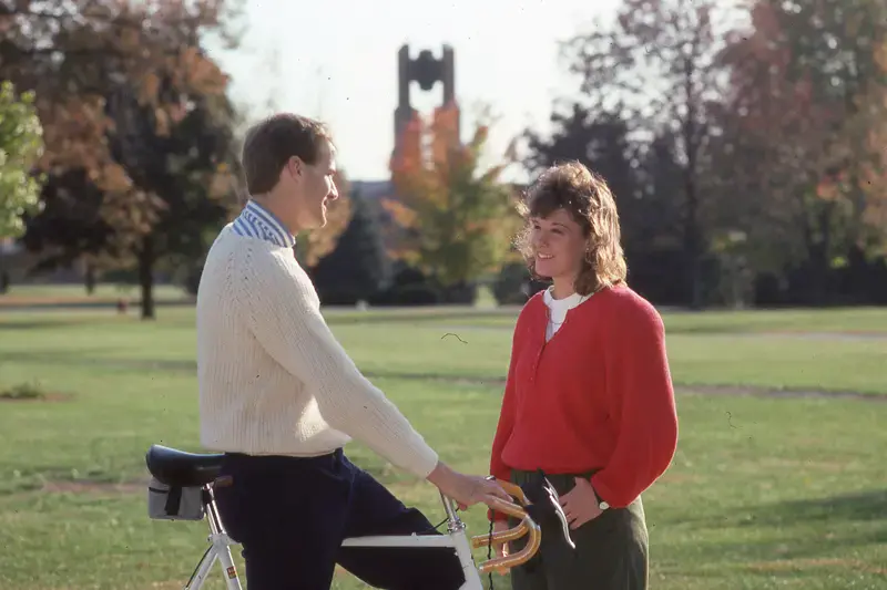 Two students talking with bell tower in background